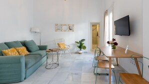 A modern living room with a green sofa, a dining table with chairs, a TV mounted on the wall, and a potted plant. - Sanlúcar de Barrameda  3 (Sanlucar de Barrameda)