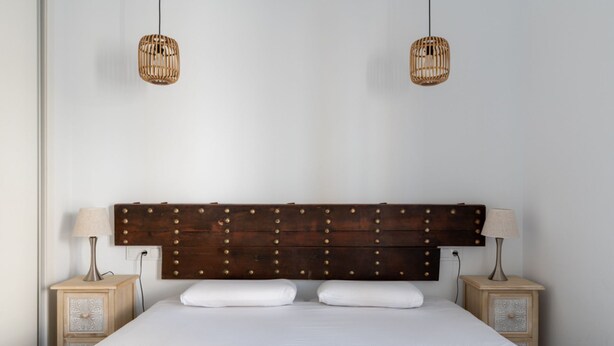 A bedroom with a wooden headboard, two bedside tables, and two wall-mounted lamps. - Sanlúcar de Barrameda  3 (Sanlucar de Barrameda)