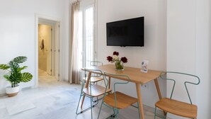 A modern dining area with a wooden table and metal chairs, a flat-screen TV mounted on the wall, and a potted plant. - Sanlúcar de Barrameda  3 (Sanlucar de Barrameda)