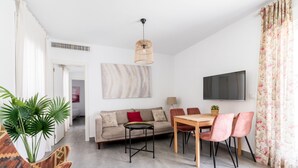A modern living room with a sofa, dining table, chairs, a TV, and a plant. - Sanlúcar de Barrameda  7 (Sanlucar de Barrameda)