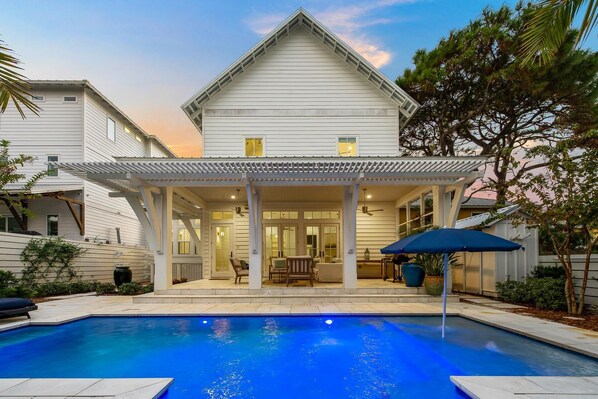 Une maison à deux étages dotée d’un patio couvert et d’une piscine.