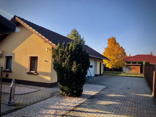 A residential building with a tiled roof, a garage, and a paved driveway.