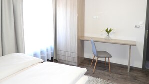 Un dormitorio con cama, escritorio, silla y armario.