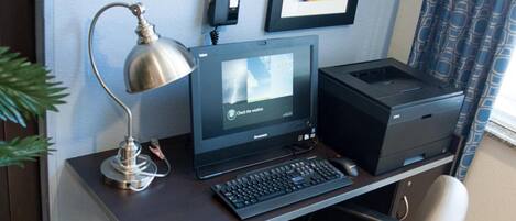 Een werkplek aan huis met een bureau, laptop, printer en stoel.