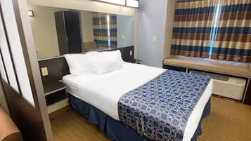 Una camera d'albergo con un letto grande, una scrivania, una sedia, uno specchio e una finestra con tende.