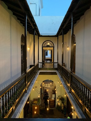 Ein Innenhof mit einer zentralen Treppe, Blick auf die Straße und einem Gebäudeeingang mit dekorativer Beleuchtung.