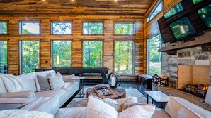 A cozy cabin interior with a stone fireplace, large windows, and a comfortable seating area. - Somethin 2 Talk About ("S2TA") (McCurtain County)