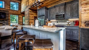 A modern kitchen with a large island, dark wood cabinets, and a stone backsplash. - Somethin 2 Talk About ("S2TA") (McCurtain County)