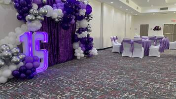 A room with a large '15' illuminated sign, white chairs with purple sashes, and a carpeted floor.