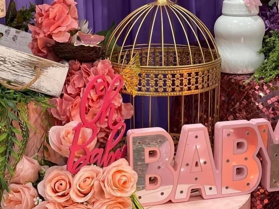 A decorative setup with a golden birdcage, pink flowers, and a 'BABY' sign.