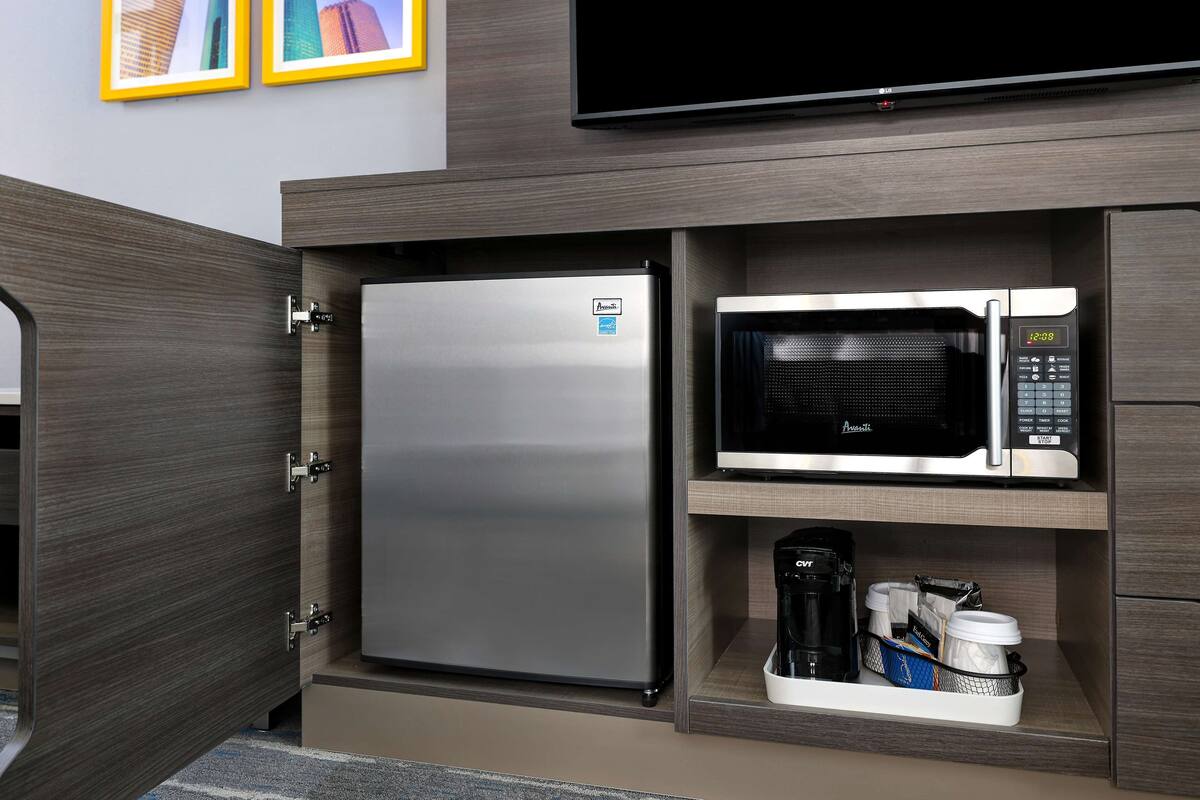 A compact kitchen with a stainless steel refrigerator, a microwave, and a coffee maker.
