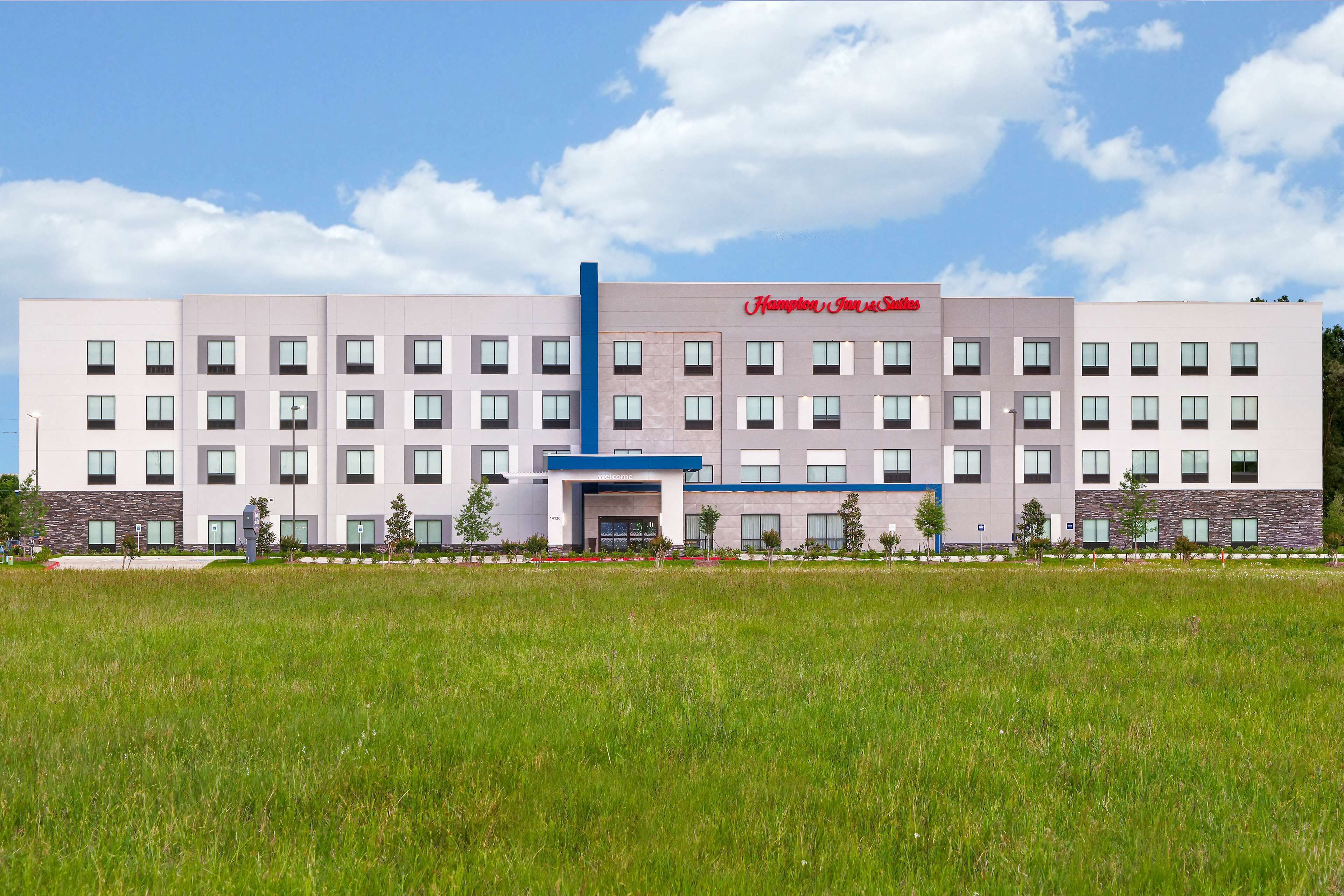 En moderne hotelbygning med en central indgang, flere etager og et fladt tag.