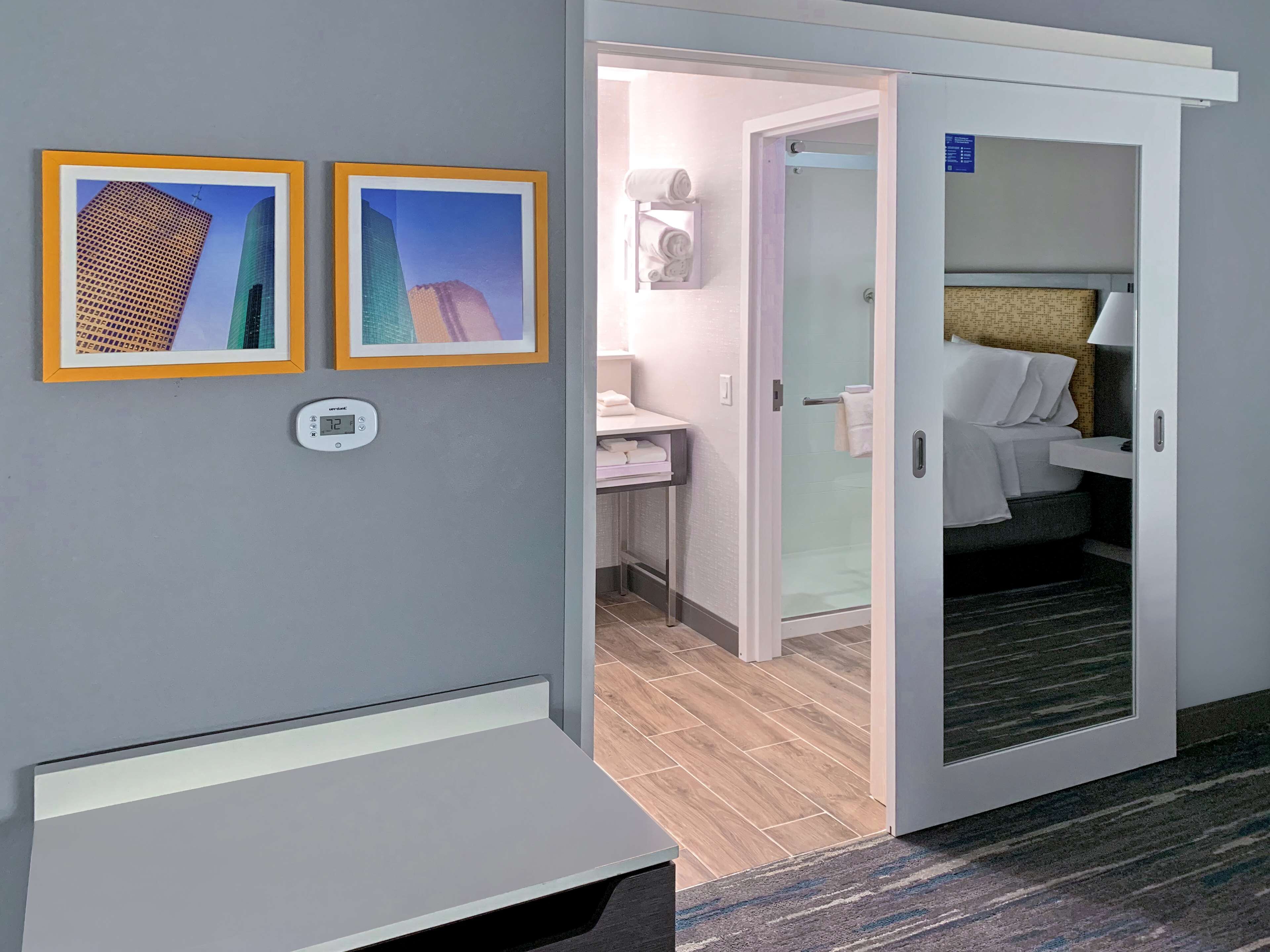 A hotel room with a bed, a bathroom, and two framed pictures on the wall.