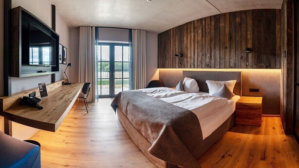 Une chambre d’hôtel moderne avec un grand lit, un bureau, une télévision et un mur en bois.