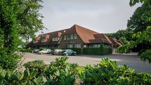 Un bâtiment sur lequel on peut lire l’inscription « Zum Zollhaus », ainsi qu’un parking où sont garées plusieurs voitures.
