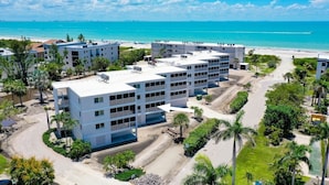 Un hotel de varios pisos con un patio central, rodeado de palmeras y vistas a la playa.