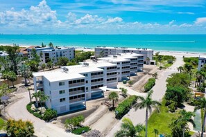 Ein mehrstöckiges Hotel mit Innenhof, umgeben von Palmen und Blick auf den Strand.