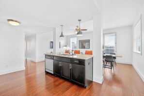 A modern kitchen with a central island, pendant lighting, and a dining area with a view.