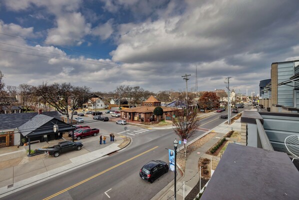 A street view with a building that has a distinct arched entrance and a small porch area.