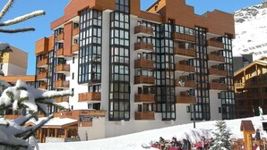 Un hotel de varios pisos con balcones, ventanas amplias y un cartel que indica que es un complejo de esquí.