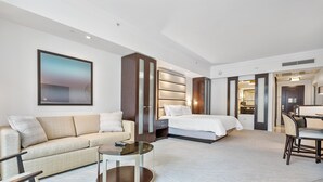 Ein modernes Hotelzimmer mit einer Couch, einem runden Couchtisch, einem Bett und einem Schreibtisch mit Stühlen.