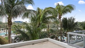 Ein Balkon mit Blick auf Palmen und einen Pool.