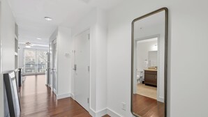 A hallway with wooden flooring, white walls, and a large mirror.