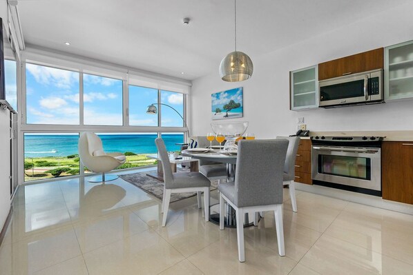 Een moderne keuken met uitzicht op zee, een eethoek met stoelen en een groot raam.