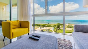 Ein modernes Hotelzimmer mit großem Fenster und Blick auf den Ozean sowie einen Golfplatz.
