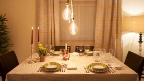 A dining table set with yellow and white plates, silverware, and wine glasses, with candles and a vase of yellow flowers. - Apt. in Pinhão, heart of Alto Douro wine region, vineyards and Douro River view (Pinhão)