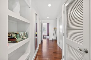A hallway with wooden flooring, white walls, and a closed door with horizontal blinds. - Coffee Shops, Restaurants, Bars & Boutiques Just Steps Away • FREE Parking • Private Balcony Overlooking 12South (Nashville)