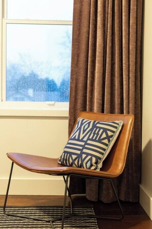 A chair with a patterned pillow, a window with curtains, and a patterned rug. - Coffee Shops, Restaurants, Bars, Salons and Boutiques, just steps away. (Nashville)