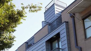 Un immeuble résidentiel moderne à plusieurs étages, doté de balcons, de grandes fenêtres et d’un jardin paysager à l’avant.