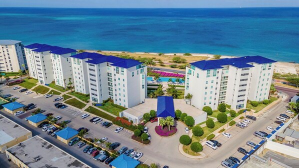 A high-rise hotel with multiple floors, a parking lot, and a pool area. - Eye Catching, Glamorous and Modern (Noord)