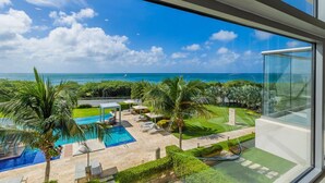 A modern hotel room with a large window overlooking a private pool and lush greenery. - A Boho Chic Oceanfront Condo for 6. (Noord)