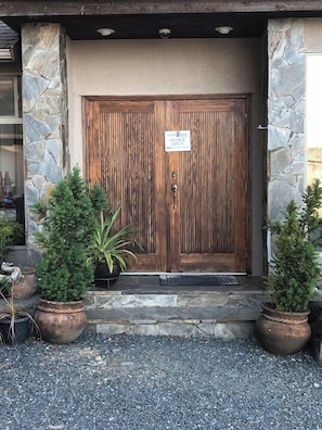 Puerta doble de madera con un cartel que indica que una oficina está abierta.