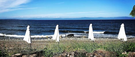 Vista sulla spiaggia con ombrelloni bianchi e lettini a righe.