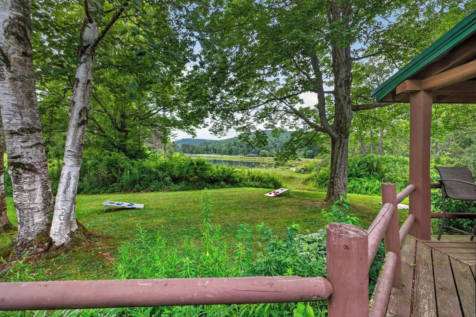 A wooden deck with a view of a grassy area and trees.