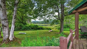 A wooden deck with a view of a grassy area and trees.