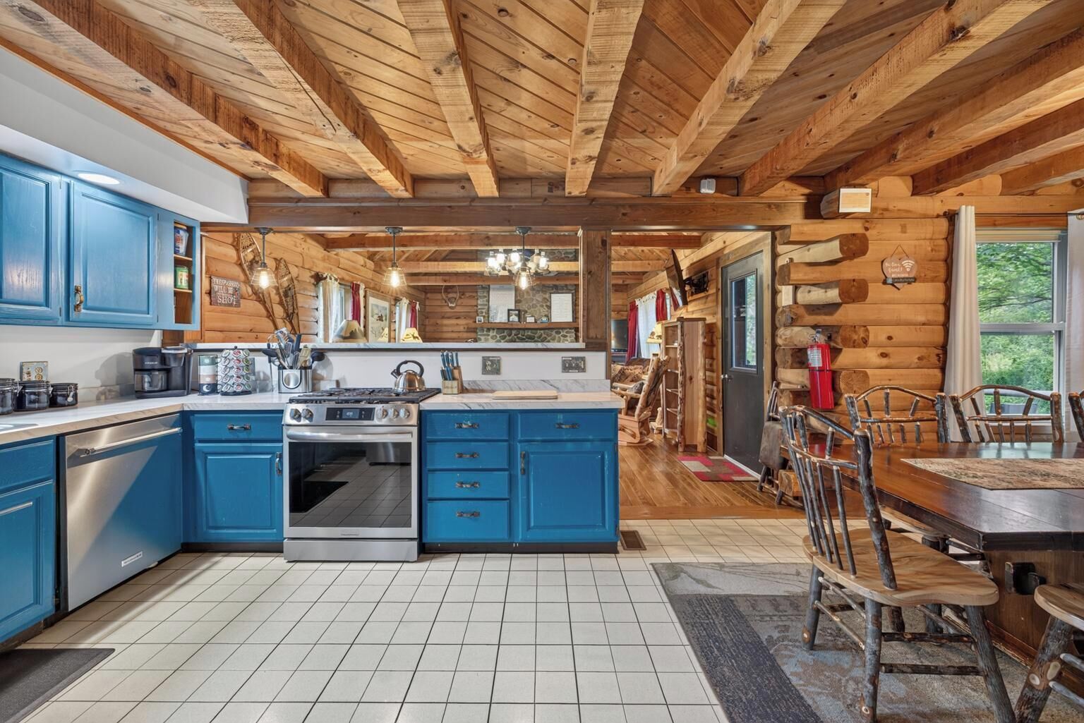 A log cabin interior with a kitchen, dining area, and a fireplace.