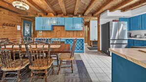 A rustic kitchen with wooden beams, blue cabinets, and a dining area with wooden chairs. - 1/2 mile to EVL, Lake, HOT TUB, Pets welcome (Ellicottville)