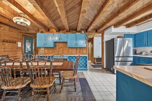 A rustic kitchen with wooden beams, blue cabinets, and a dining area with wooden chairs. - 1/2 mile to EVL, Lake, HOT TUB, Pets welcome (Ellicottville)