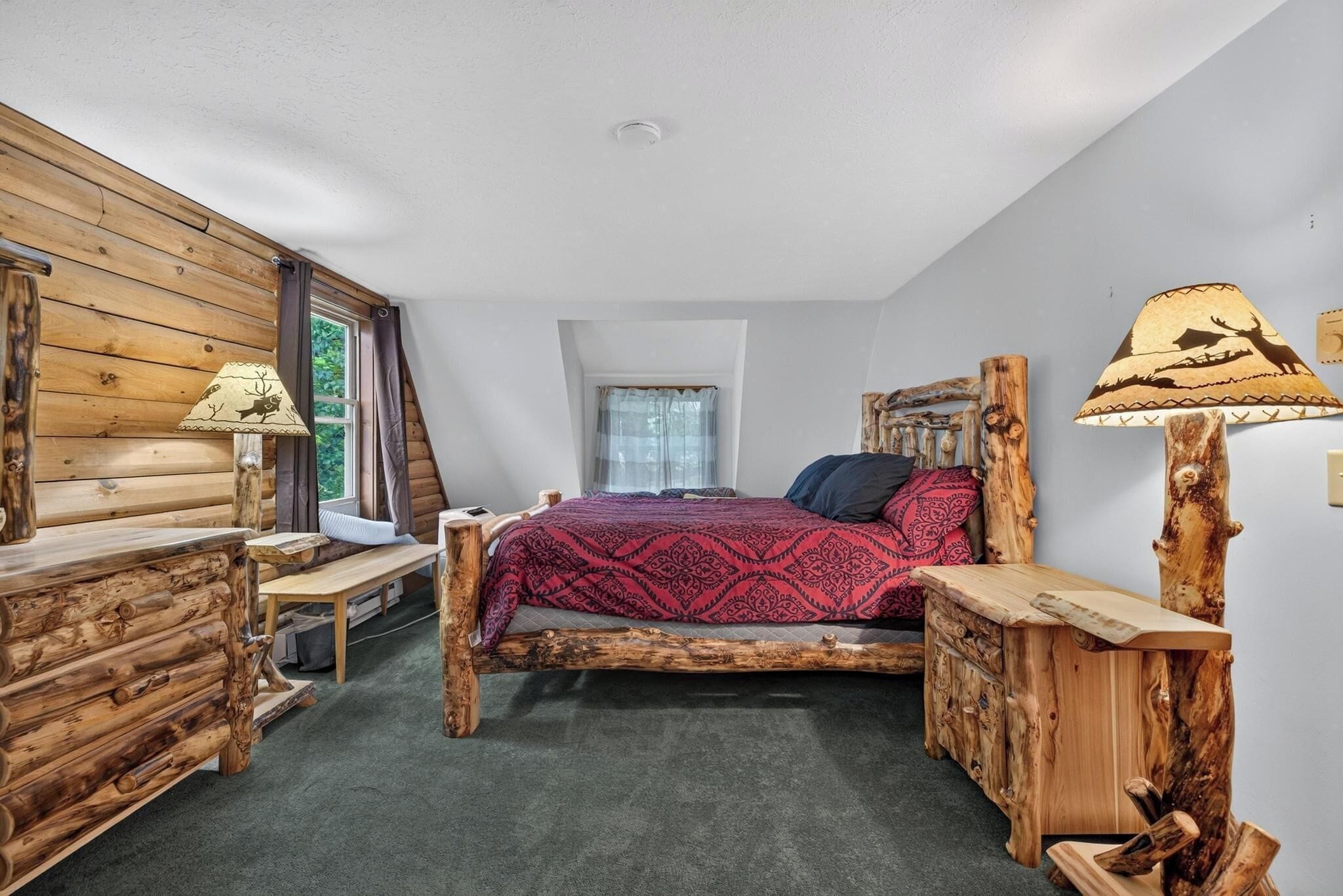A log cabin-style bedroom with a bed, wooden nightstands, and a lamp.