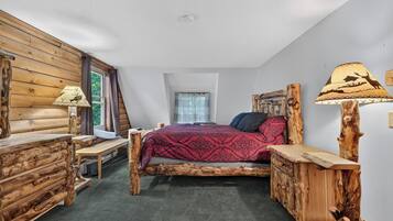 A log cabin-style bedroom with a bed, wooden nightstands, and a lamp.