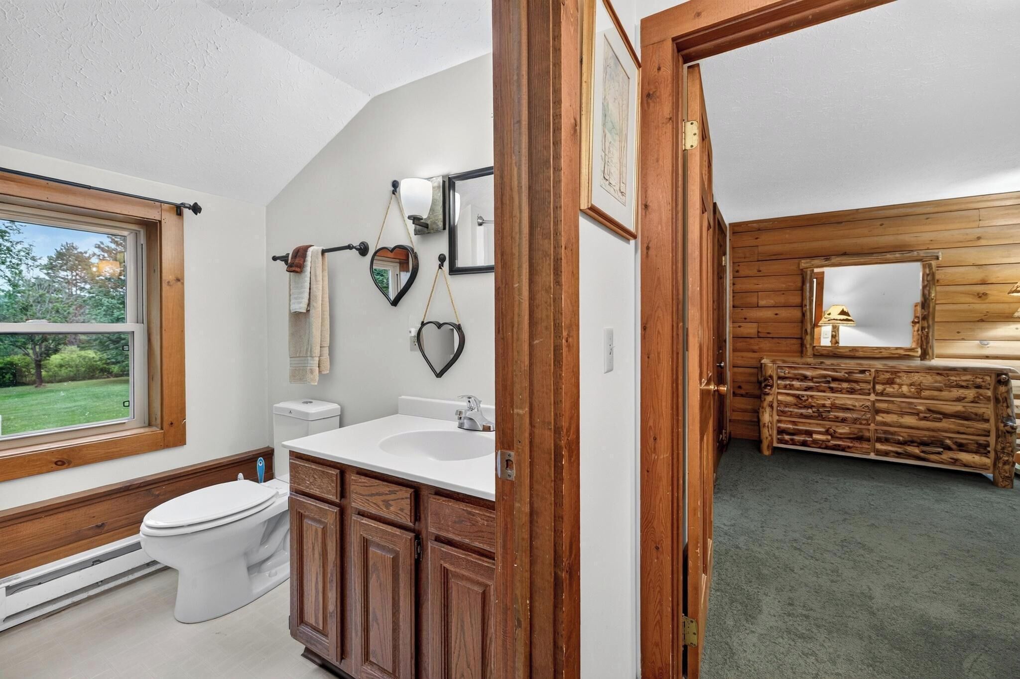 A bathroom with a toilet, sink, and wooden cabinets.