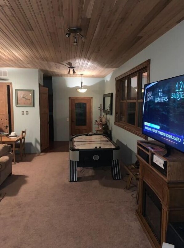 Une pièce équipée d’une table de billard, d’un téléviseur et d’un ventilateur de plafond.
