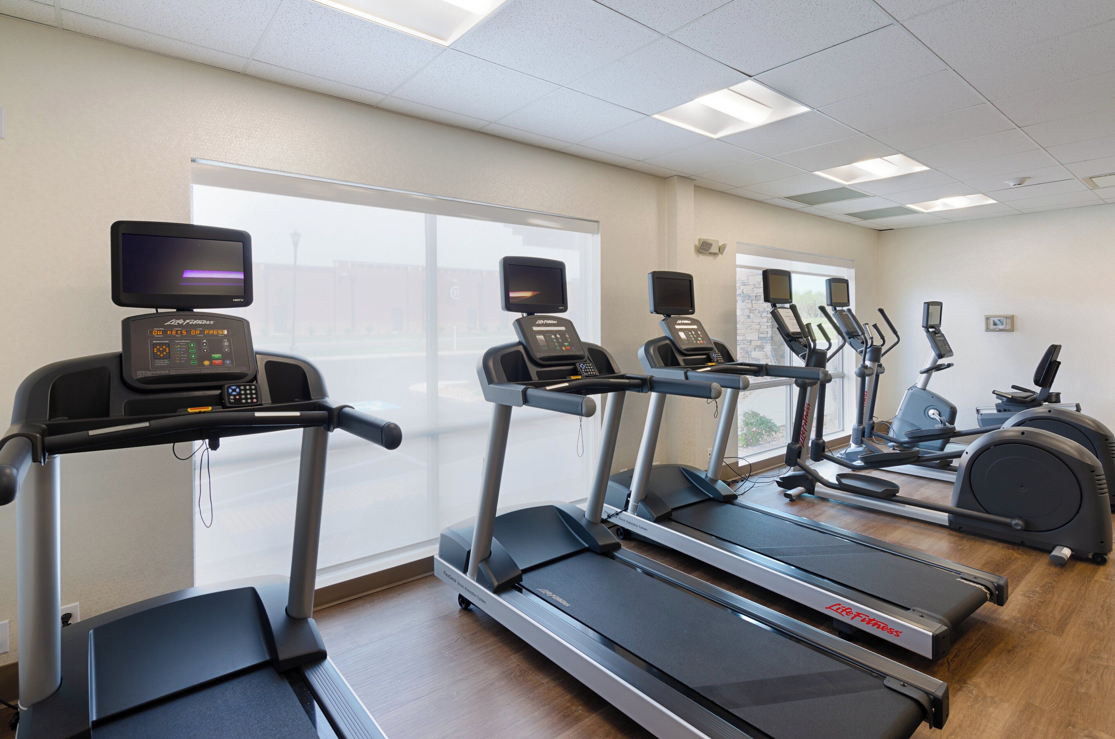 Un gimnasio con cintas de correr, elípticas y una bicicleta estática.