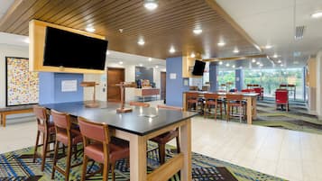A conference room with a large table, chairs, and a TV screen.