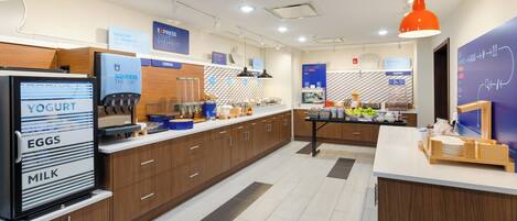 A modern kitchen with a refrigerator labeled 'YOGURT, EGGS, MILK', a coffee machine, and a breakfast bar.
