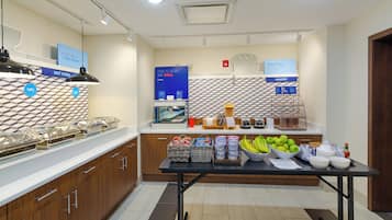 A modern kitchen with a buffet setup, including a counter with food items and a display of breakfast options.